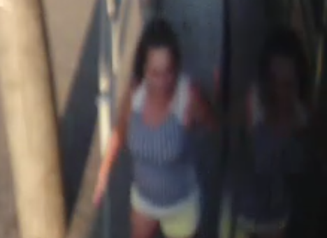zdjęcie kolorowe: zapis z monitoringu tramwajowego zniekształcony wizerunek kobiety w długich ciemnych włosach spiętych w kucyk, ubranej w żółte krótkie szorty i bluzkę biało-niebieską bez rękawów