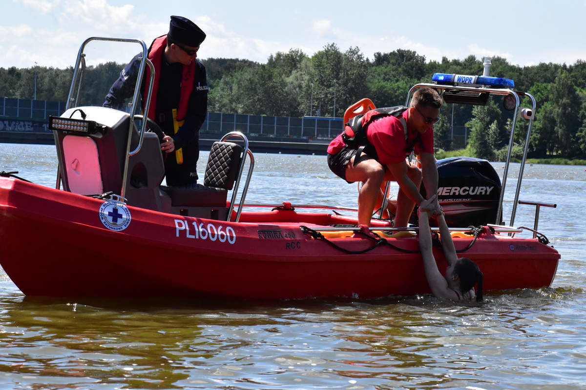 zdjęcie kolorowe: policjant współpracujący z ratownikiem wodnym wyciągający pozoranta z wody