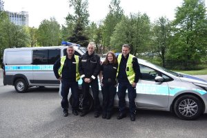 dwóje policjantów z Niemiec stoi wraz dwoma policjantami z Polski a za nimi stoją radiowozy