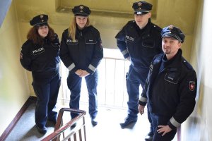 Niemieccy policjanci stoją na klatce schodowej budynku mieszkalnego.