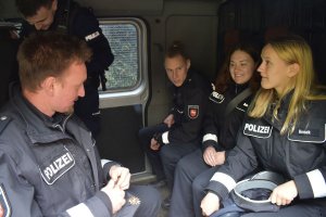 niemieccy i polscy policjanci siedzą w radiowozie typu fiat ducato