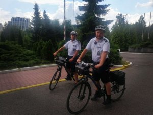 Na zdjęciu widać dwóch policjantów na rowerach za nim są drzewa