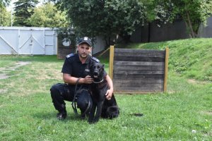 na zdjęciu widać przewodnika psa służbowego wraz z psem rasy owczarek niemiecki maści czarnej