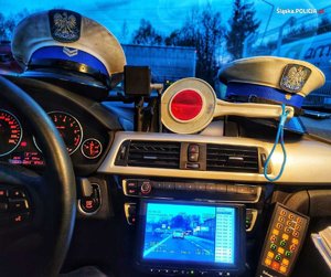 zdjęcie kolorowe: dwie policyjne czapki policjantów ruchu drogowego w radiowozie