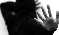zdjęcie czarno-białe: postać człowieka zasłaniająca dłońmi swoje ciało