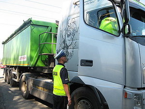 zdjęcie kolorowe: policjant drogówki podczas kontroli drogowej cieżarówki